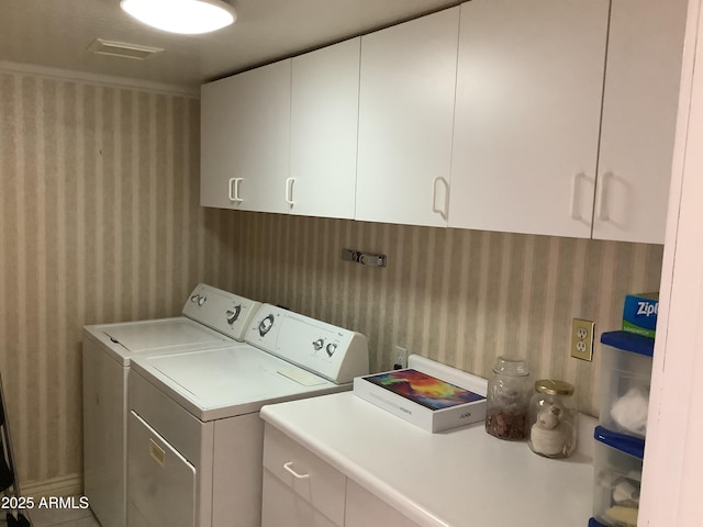 washroom with visible vents, wallpapered walls, cabinet space, and washer and dryer