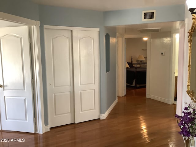 hall featuring wood finished floors, visible vents, and baseboards