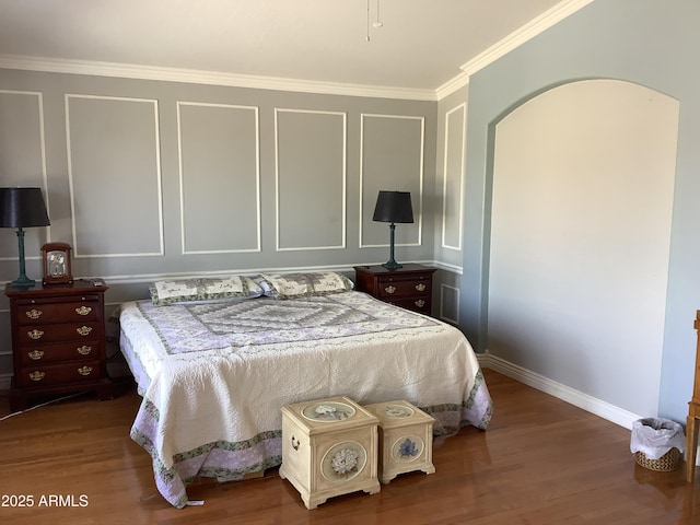 bedroom featuring arched walkways, crown molding, baseboards, and wood finished floors