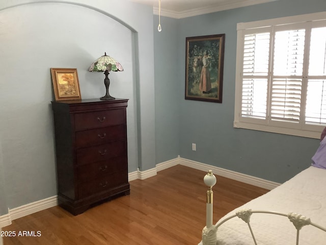 bedroom with baseboards, wood finished floors, and ornamental molding