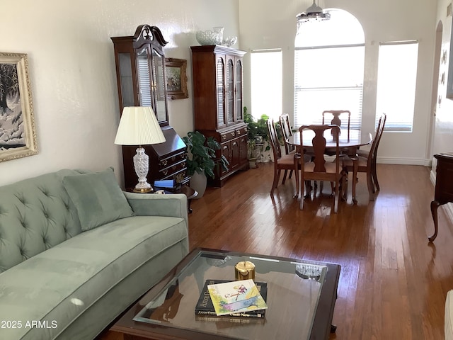 living area with arched walkways and wood finished floors