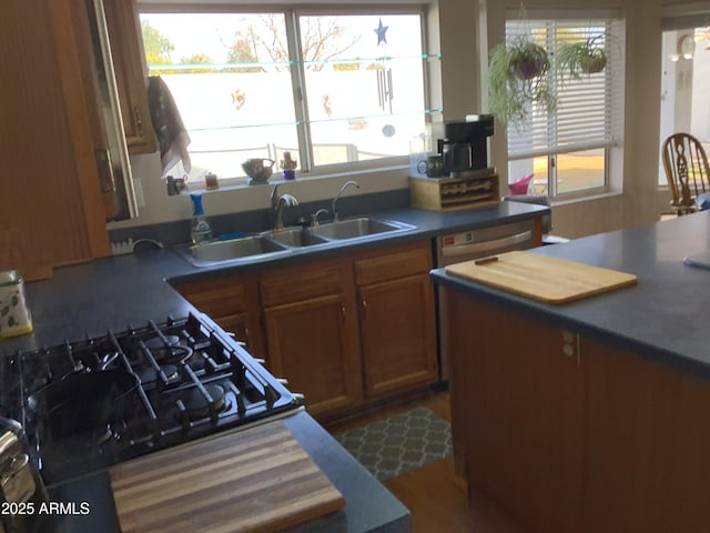 kitchen featuring a healthy amount of sunlight, dark countertops, brown cabinets, and a sink