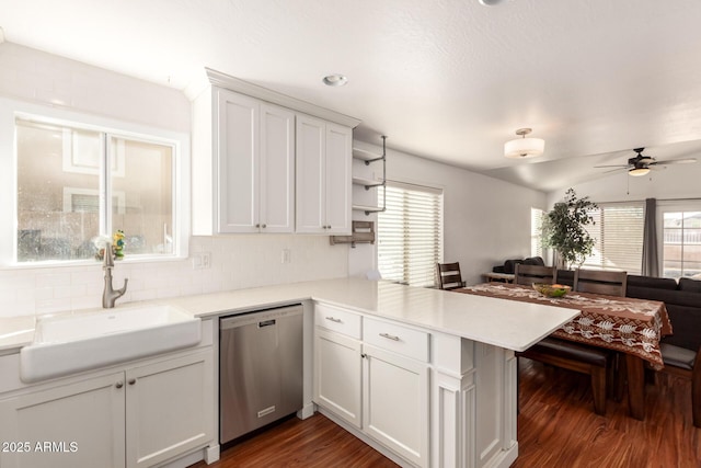 kitchen with light countertops, stainless steel dishwasher, white cabinetry, a sink, and a peninsula