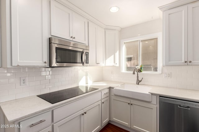 kitchen featuring stainless steel appliances, backsplash, a sink, and white cabinetry