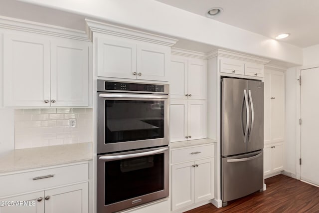 kitchen featuring tasteful backsplash, white cabinetry, stainless steel appliances, and light stone counters