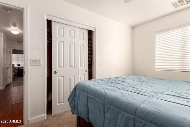 carpeted bedroom featuring baseboards, visible vents, and a closet