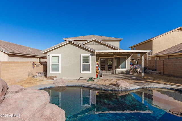 rear view of house with a fenced in pool, a patio area, a fenced backyard, and stucco siding