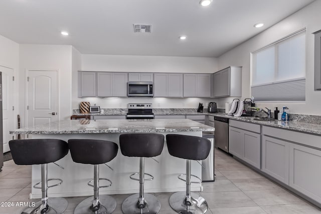 kitchen featuring appliances with stainless steel finishes, a center island, sink, and light stone counters