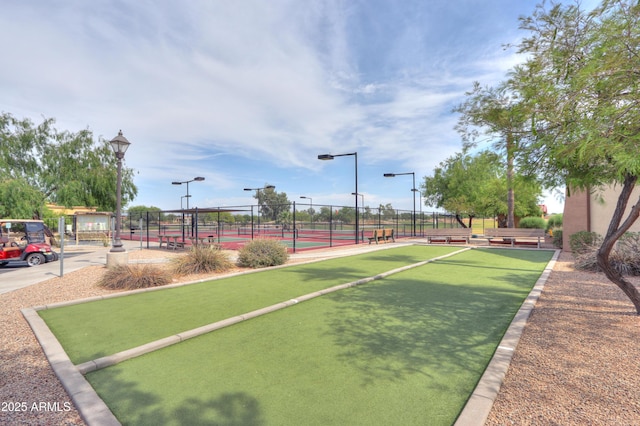 view of property's community featuring a tennis court and fence