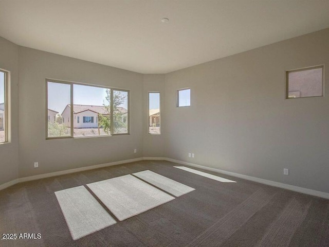 carpeted empty room featuring baseboards