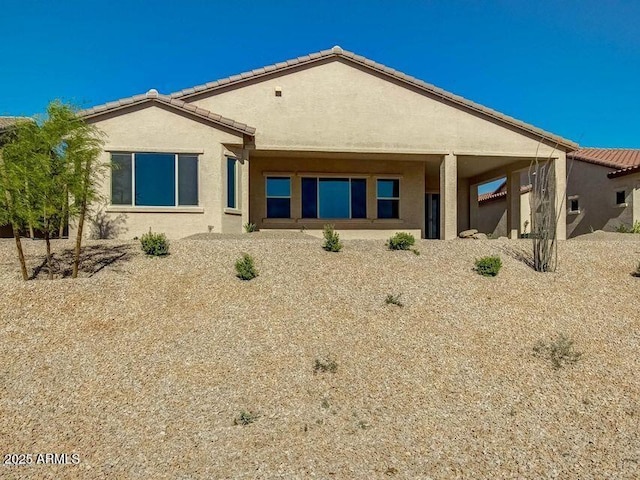 back of property with stucco siding and a tiled roof