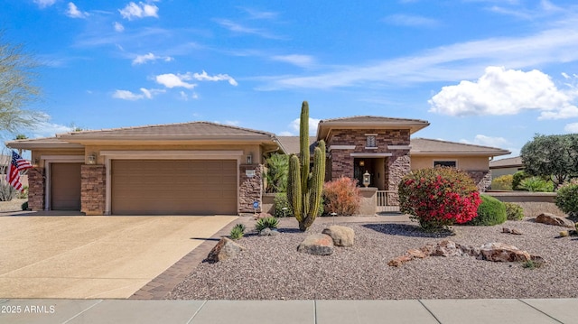 prairie-style home featuring stucco siding, driveway, stone siding, an attached garage, and a tiled roof