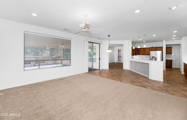 unfurnished living room with visible vents, carpet flooring, recessed lighting, a ceiling fan, and a sink