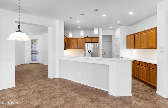 kitchen with brown cabinets, stainless steel refrigerator with ice dispenser, decorative light fixtures, recessed lighting, and a peninsula