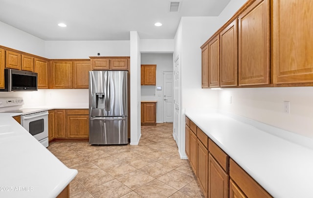 kitchen with visible vents, recessed lighting, appliances with stainless steel finishes, brown cabinetry, and light countertops