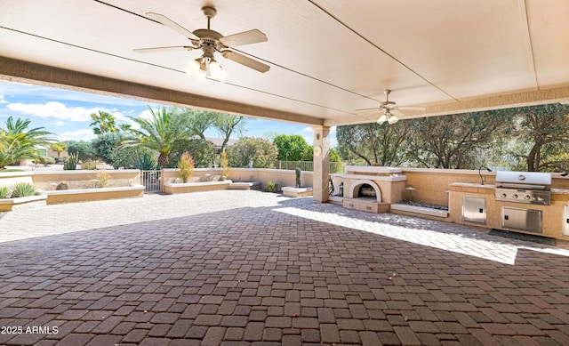 view of patio / terrace with fence, exterior kitchen, exterior fireplace, a grill, and a ceiling fan