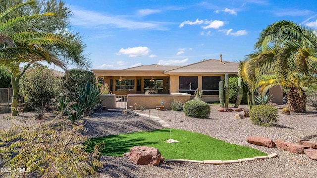 rear view of property featuring stucco siding and fence