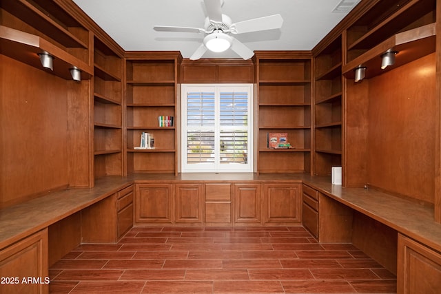 unfurnished office with wood finish floors, built in desk, and ceiling fan