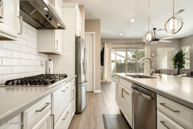 kitchen featuring appliances with stainless steel finishes, decorative light fixtures, white cabinetry, sink, and ceiling fan