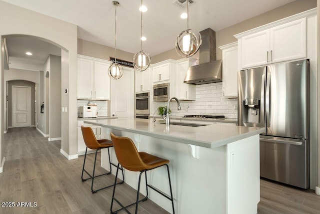 kitchen with a center island with sink, stainless steel appliances, and white cabinetry