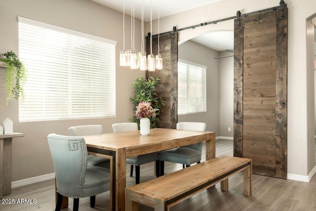 dining area with light hardwood / wood-style floors and a barn door