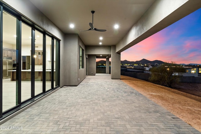 patio terrace at dusk with a mountain view and ceiling fan