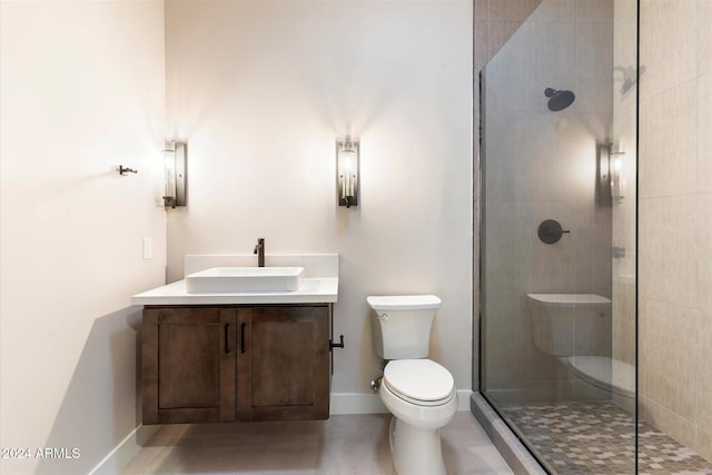 bathroom with tiled shower, vanity, and toilet