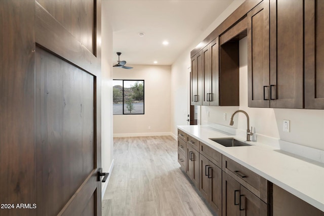 kitchen with dark brown cabinets, light hardwood / wood-style flooring, ceiling fan, and sink