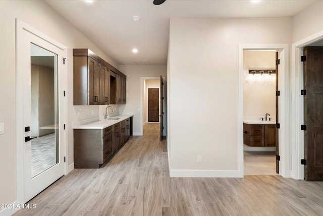 kitchen with dark brown cabinets, light wood-type flooring, and sink