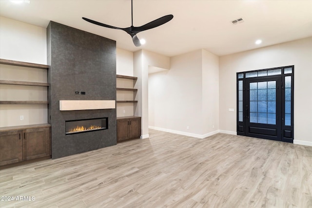 unfurnished living room featuring ceiling fan, light wood-type flooring, and a fireplace