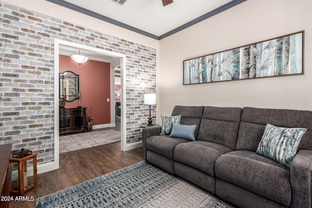 living room with dark hardwood / wood-style flooring, crown molding, and brick wall