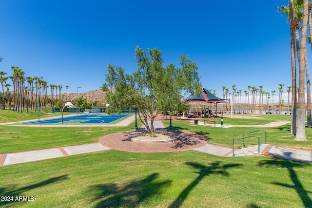 view of home's community with a yard, a gazebo, basketball hoop, and a water view