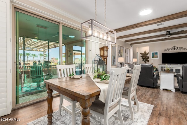 dining area featuring beamed ceiling, ornamental molding, dark wood-type flooring, and ceiling fan