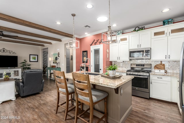 kitchen featuring sink, decorative light fixtures, stainless steel appliances, a kitchen island with sink, and white cabinets