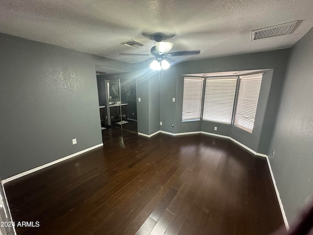 unfurnished room featuring dark wood-type flooring, a textured ceiling, and ceiling fan