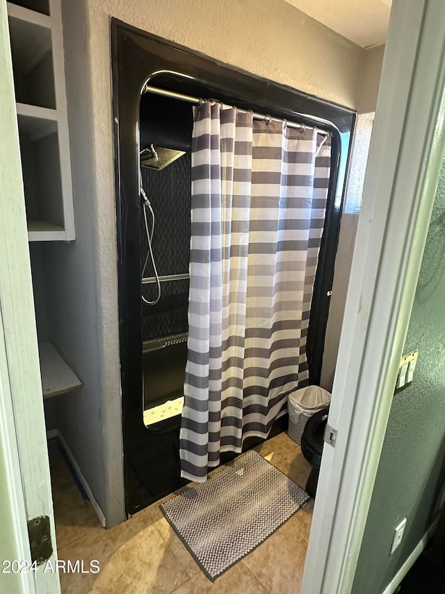 bathroom featuring toilet, a shower with curtain, and tile patterned floors