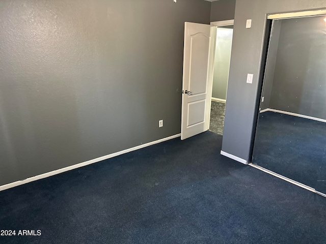 unfurnished bedroom featuring a closet and dark carpet