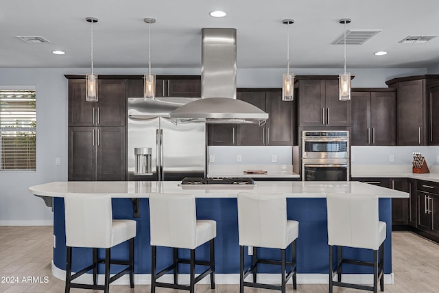 kitchen featuring pendant lighting, island range hood, light hardwood / wood-style flooring, and a kitchen island with sink