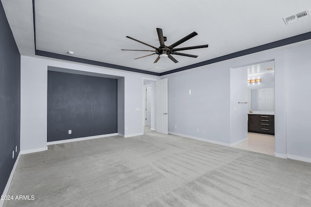 unfurnished bedroom featuring ceiling fan, light carpet, and ensuite bath