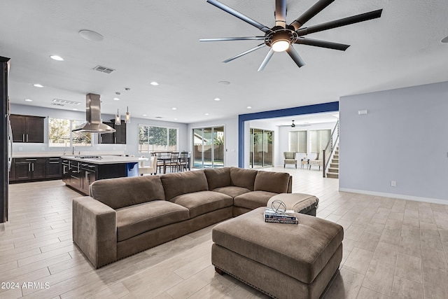 living room with ceiling fan, light hardwood / wood-style floors, and a textured ceiling