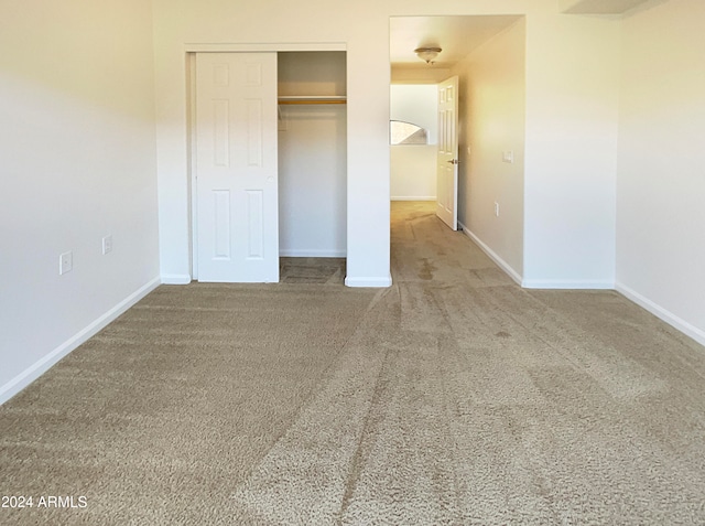 unfurnished bedroom with light colored carpet and a closet