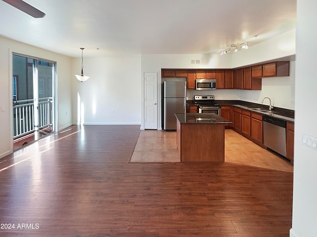 kitchen with light wood-type flooring, hanging light fixtures, stainless steel appliances, and sink