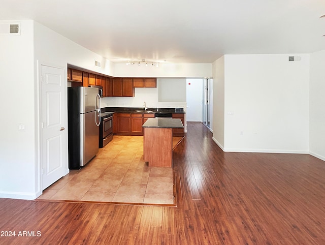 kitchen featuring a kitchen island, electric stove, light tile floors, stainless steel fridge, and sink