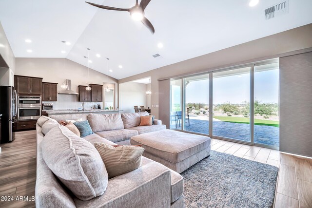 kitchen with lofted ceiling, a kitchen island with sink, sink, appliances with stainless steel finishes, and light hardwood / wood-style floors