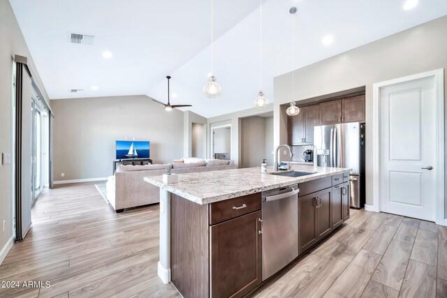 kitchen featuring light wood-type flooring, wall chimney range hood, decorative light fixtures, stainless steel fridge with ice dispenser, and an island with sink