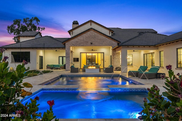 pool at dusk featuring an in ground hot tub, an outdoor living space, pool water feature, and ceiling fan