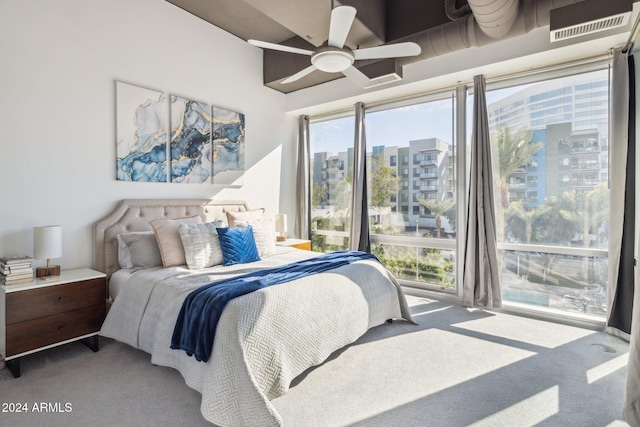 carpeted bedroom featuring multiple windows, a city view, ceiling fan, and visible vents