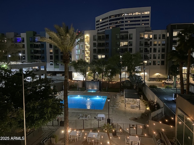 property at night featuring a community pool and a view of city lights