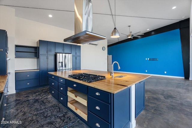 kitchen featuring blue cabinets, an island with sink, island exhaust hood, gas stovetop, and stainless steel fridge with ice dispenser