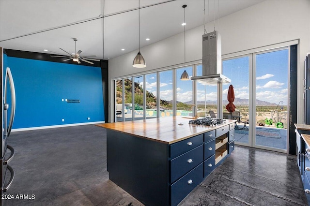 kitchen with butcher block countertops, island exhaust hood, stainless steel appliances, finished concrete floors, and a mountain view